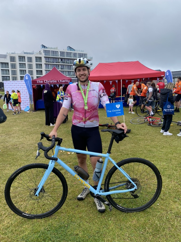 Luke after a cycling event with his bike and a medal round his neck